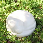 Satin white porcelain ceramic urn sculpture of a sleeping dog outside