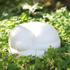 Satin white porcelain ceramic urn sculpture of a sleeping dog outside