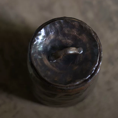 Close-up top view of glazed brown-bronze-black artisanal stoneware pet urn