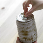 Hand holding glazed white brown artisanal pet urn with organic shape and color patterns