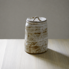 Glazed white artisanal pet urn with organic shape and color patterns on table