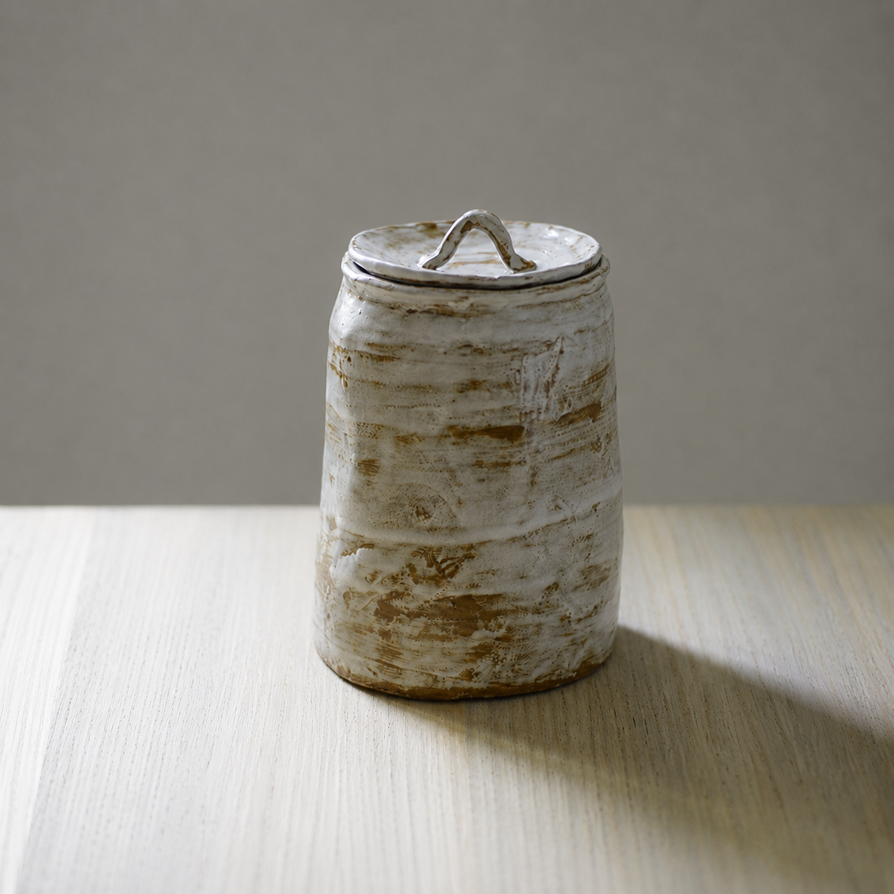 Glazed white artisanal pet urn with organic shape and color patterns on table